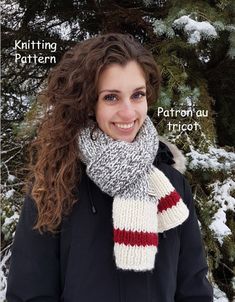 a woman standing in the snow wearing a knitted scarf with stripes on it and smiling at the camera