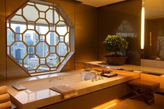 a bath room with a large window next to a sink and a bath tub in front of a mirror