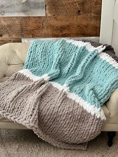 a couch with a blanket on top of it in front of a wooden headboard