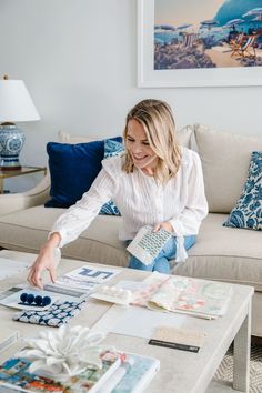 a woman sitting on a couch in front of a coffee table filled with pictures and cards