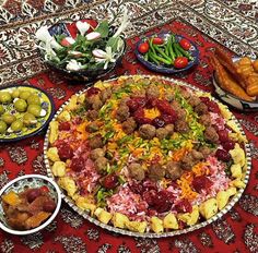 a large platter filled with meatballs, vegetables and other foods on a table