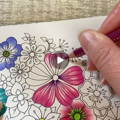 someone is drawing flowers with colored pencils on the paper and using markers to draw them