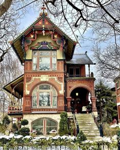 an old victorian style house in the winter with snow on the ground and stairs leading up to it