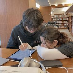 two people sitting at a table in front of a tablet computer and headphones on