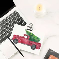 an open laptop computer sitting on top of a white desk next to a christmas tree