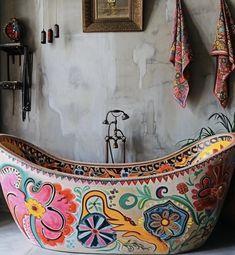 an ornate bathtub is decorated with colorful flowers and leaves, along with towels hanging on the wall