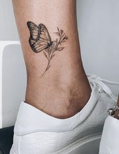 a woman's foot with a butterfly tattoo on the side of her leg,