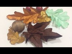 three different colored leaves and two acorns on a white surface with gold glitter