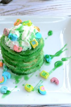 a stack of green cake with white frosting and sprinkles