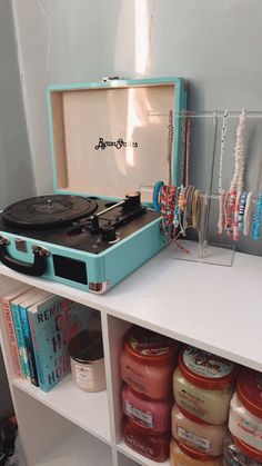 a record player sitting on top of a white shelf next to jars and bracelets