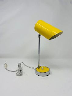 a yellow table lamp sitting on top of a white floor next to a charger