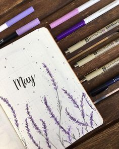 an open notebook with purple flowers and writing on the page next to some pencils