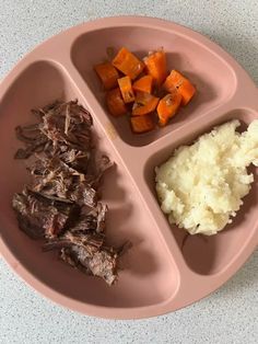 a pink plate topped with meat, mashed potatoes and carrots