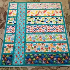 a quilted table runner made with colorful strips and fish on the border, sitting on top of a floral fabric