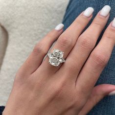 a woman's hand with a diamond ring on her left hand and white nails