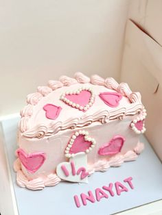 a pink cake with hearts on it sitting in a box