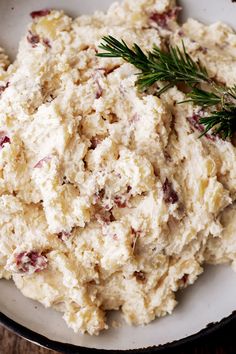 a bowl filled with mashed potatoes and topped with a sprig of rosemary