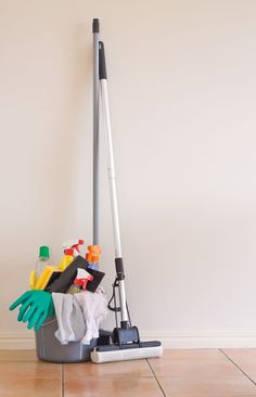 a mop and cleaning supplies sitting on the floor in front of a white wall