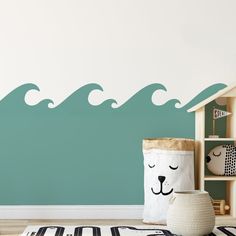 a room with a wall that has waves painted on it and a stuffed animal in the corner