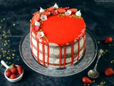 a red and white cake with strawberries on the top is sitting on a plate