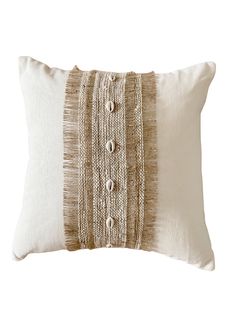 a white and brown pillow with buttons on the front, sitting against a white background