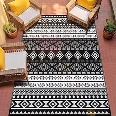 a black and white area rug with yellow pillows on it next to wicker chairs