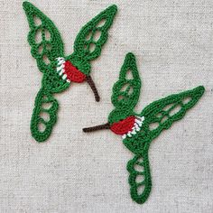 two green crocheted hummingbirds with red and white wings