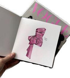 a hand holding an open book with a pink bow on the front and back cover