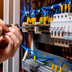 a person is working on an electrical panel with wires and plugs in the background