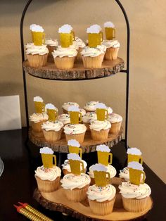 cupcakes with frosting and beer mugs are arranged on a tiered tray