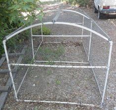 an old metal bed frame sitting in the middle of a gravel road next to a car