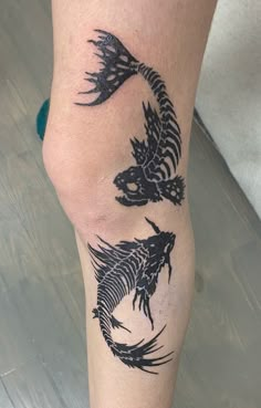 a person with a tattoo on their leg that has two fish in the shape of a dragon