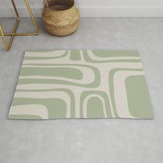 a green and white area rug on the floor next to a basket with a plant in it