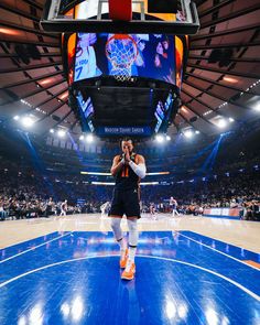 a man standing on top of a basketball court in front of an arena filled with people