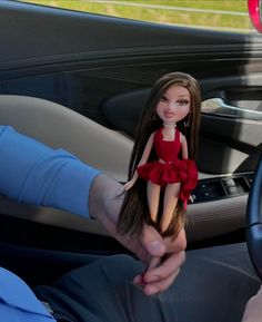 a doll is sitting in the driver's seat of a car, being held by a man