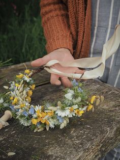 a person is tying a flower crown on a piece of wood