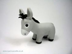 a small toy donkey with a black bow on its head, standing in front of a white background