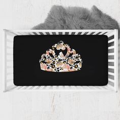 a black and white baby crib with a crown on it's head in front of a gray teddy bear