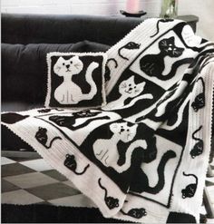 a black and white cat afghan sitting on top of a couch