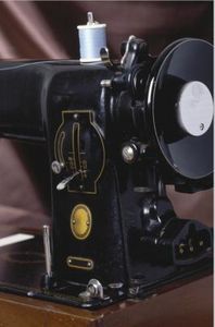 an old black sewing machine sitting on top of a wooden table