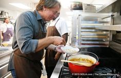 two men in aprons preparing food inside of a kitchen