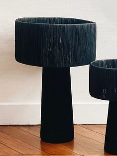 two black vases sitting on top of a wooden floor