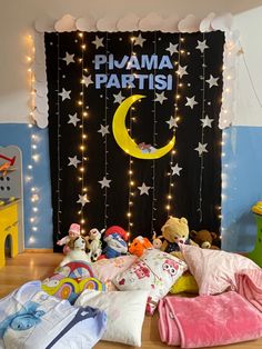 there are many stuffed animals on the floor in front of a wall with lights and decorations