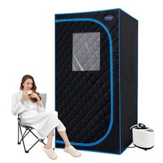 a woman sitting in a chair next to a portable shower and holding a hot drink