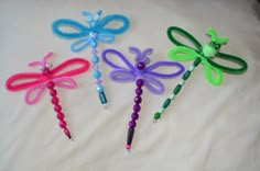 four different colored dragon wands on a white sheet