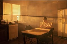 a man sitting at a table in front of a refrigerator with steam coming from it