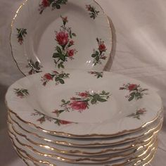 a stack of white and gold plates with roses on them