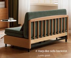 a green couch sitting in front of a window next to a wooden table with a cup on it