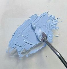 a paintbrush is being used to paint a piece of white paper with light blue acrylic