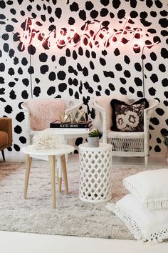 a living room with black and white wallpaper, two chairs and a coffee table